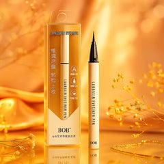 BOB liquid eyeliner with precise brush tip in gold packaging on warm golden background, beauty essential